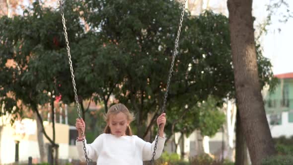 Happy Girl, Having Fun On Swing In Park at Sunset. alt
