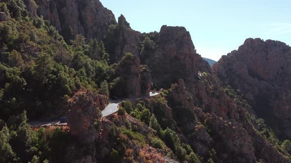 Panoramic Aerial View of Rocky Red Mountain Canyon with Electric Car Driving in a Curved Road in a alt