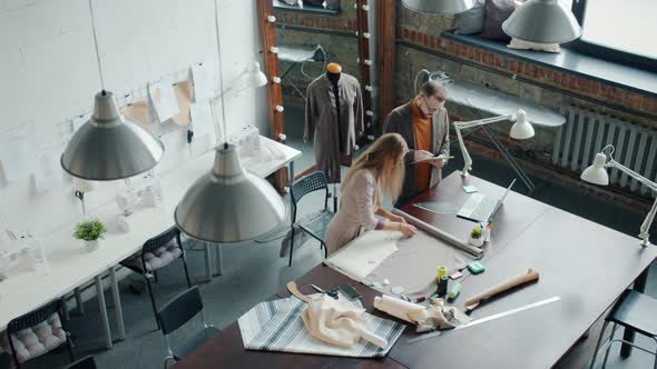 Top View of Tailors Man and Woman Working in Studio Talking Making New Garments alt