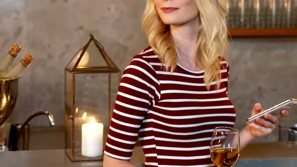 Young woman using her mobile phone while holding champagne glass in her hand 4K 4k alt