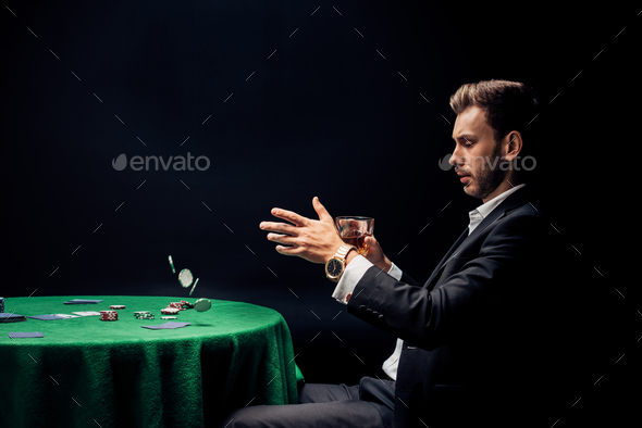 handsome man throwing in air poker chips on black
