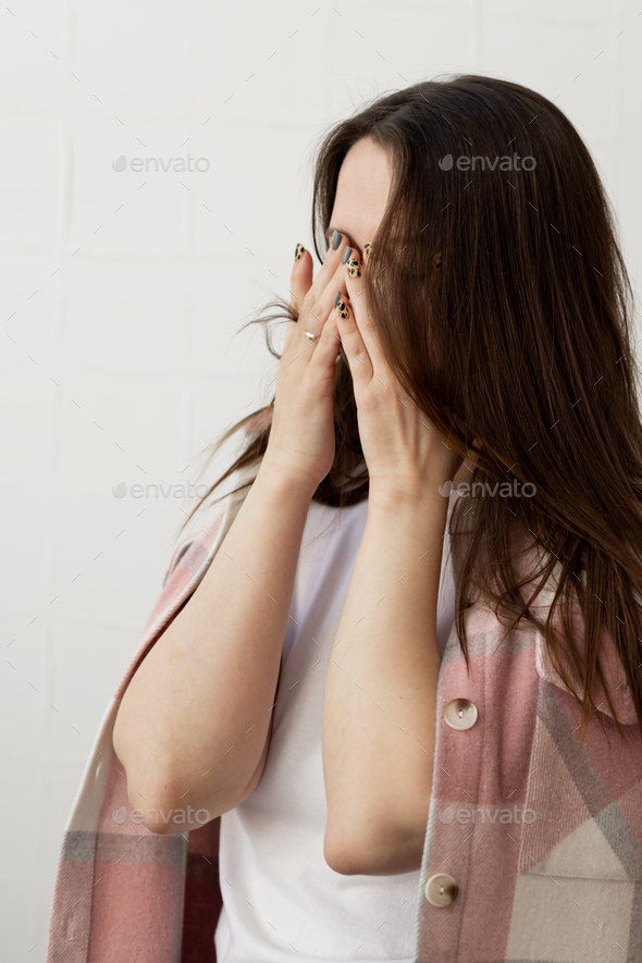 Young beautiful woman crying with her hands over her eyes and turning away from the camera