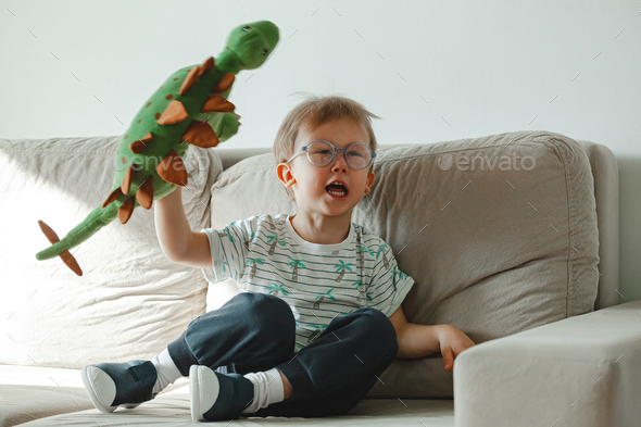 A child with autism in glasses sits on the sofa and sad, angry a