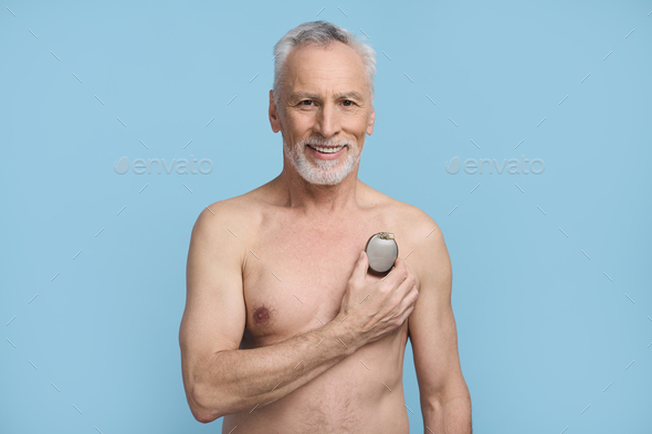 Smiling happy senior man holding a pacemaker on blue background. Cardiac surgery Healthcare Medicine