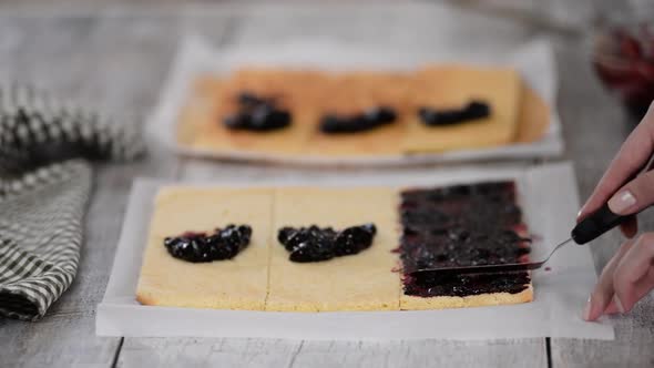 Girl Spreading Jam on a Flat Sheet of Cake To Make a Cake with Vertical Layers at Home alt