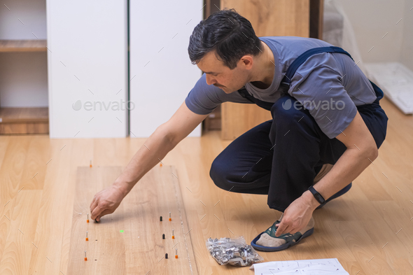 Furniture delivery and assembling strong hands of carpenter screwing nails into wooden cabinet