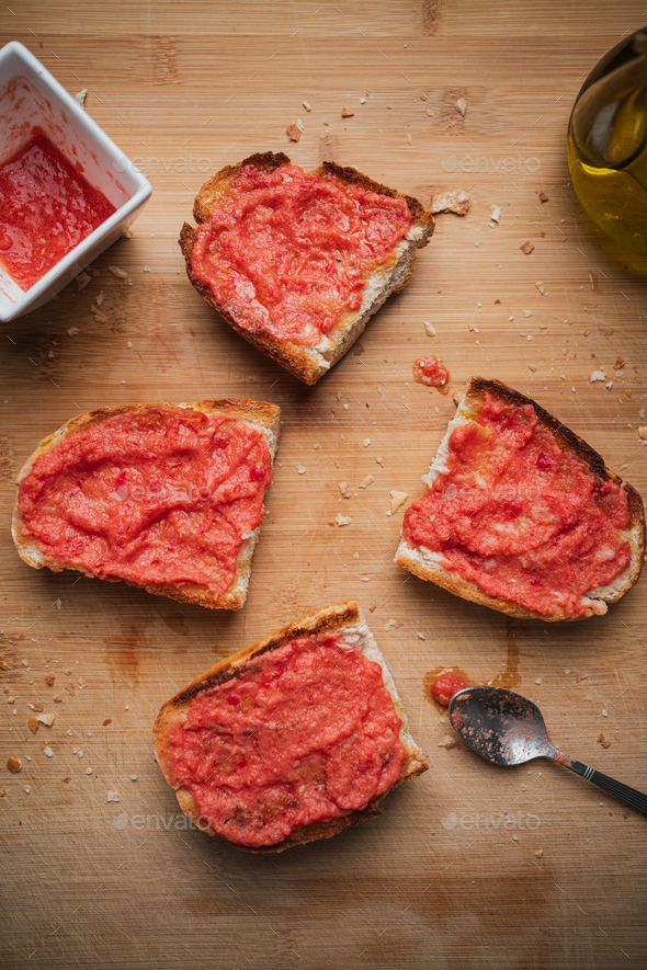 Four spanish tomato toasts on a wooden table with olive oil and crushed tomato. Spanish breakfast.