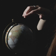  a young girl in a dark room holding a globe in her hands and looking for countries on it - PhotoDune Item for Sale