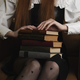  young woman sitting in a chair in a dark in the room and holds a stack of old books - PhotoDune Item for Sale