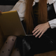 a young girl is sitting in a chair in the evening in the room, on her lap she has a laptop - PhotoDune Item for Sale