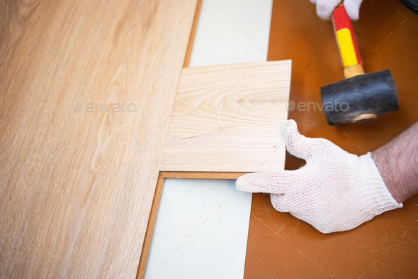 hammer puts the floorboard in place, professional laying of flooring, laminate