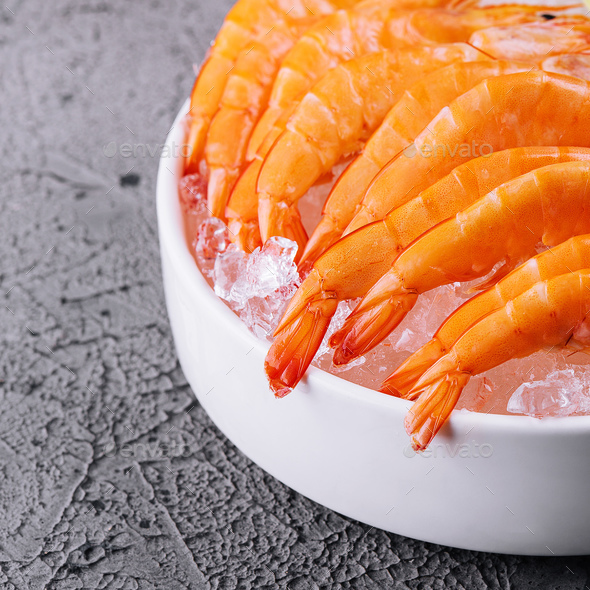 A group of tiger shrimp on a bowl of ice with lime