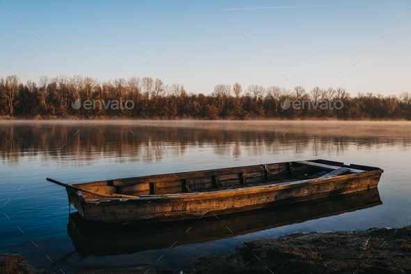 Old wooden boat on the water of a calm lake at sunrise