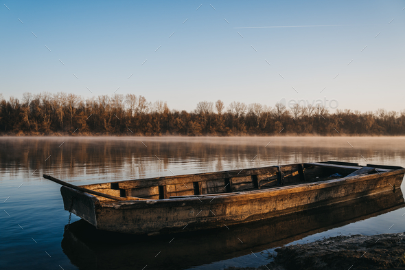 Old wooden boat on the water of a calm lake at sunrise