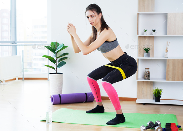 Woman during her fitness workout at home with rubber resistance band
