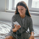 beautiful woman  using smartphone and sitting on the bed, woman with phone indoors portrait - PhotoDune Item for Sale