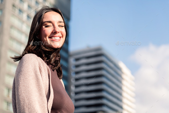 smiling young woman looking at camera on sunny day - Stock Photo - Images