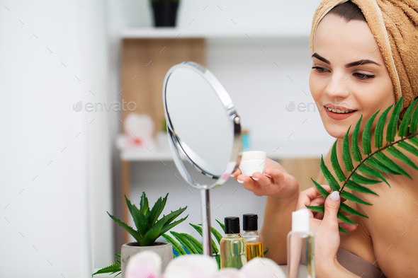 Cute girl puts makeup on the face in the bathroom