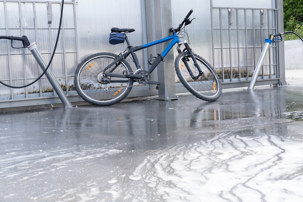 Washing a bicycle with a foam jet at a car wash. The bike is covered with foam. Self-service