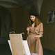Girl in dress and black hat painting on an easel in a city on a street - PhotoDune Item for Sale