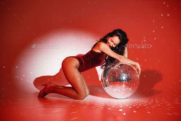Young woman salsa dancer posing under a red projector\'s light