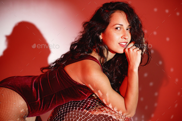 Young woman salsa dancer posing under a red projector\'s light