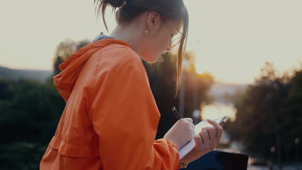 A Young Responsible Student Writes Down New Ideas for the Project in Her Notebook Stops Thoughtfully alt
