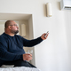 Overweight exhausted man drinks water switches on air conditioner at home in summer. - PhotoDune Item for Sale