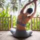 Rear view of woman doing yoga, bending side body sitting on the floor at tropical vacation resort. - PhotoDune Item for Sale