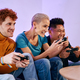 A group of friends sitting on the sofa with a controller in their hand playing video games - PhotoDune Item for Sale