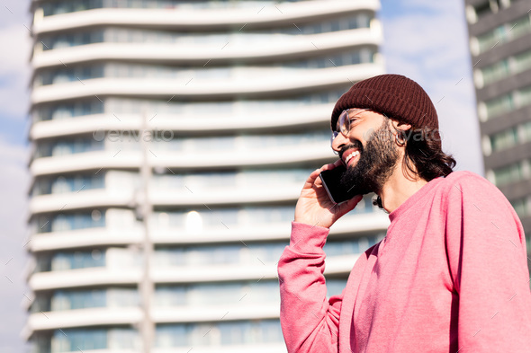 joyful young guy on phone in bright city morning - Stock Photo - Images