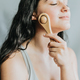 Young woman applying facial massage with wooden roll. Applying pressure to improve circulation - PhotoDune Item for Sale