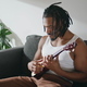 Expressive guitarist playing ukulele domestic place. Man relaxing enjoying music - PhotoDune Item for Sale