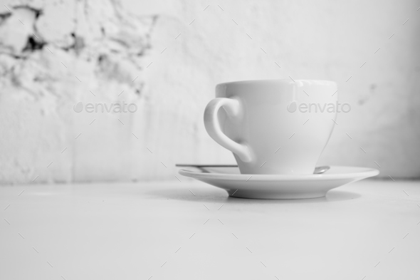Black and white photo of white cup in front of brick wall - Stock Photo - Images