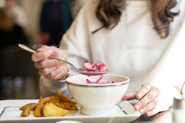 Woman eating cold soup holodnik in a cafe. Female eating beetroot soup with fried potatoes in a rest - Stock Photo - Images