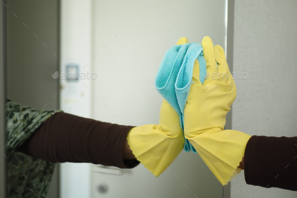 close up of person hand in gloves cleaning window glass Stock