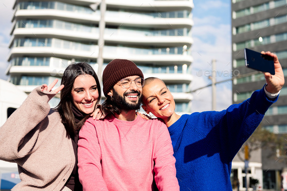 three smiling friends taking a selfie in the city - Stock Photo - Images