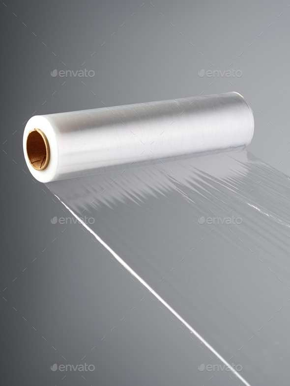 Roll of transparent polyethylene cling film on gray background