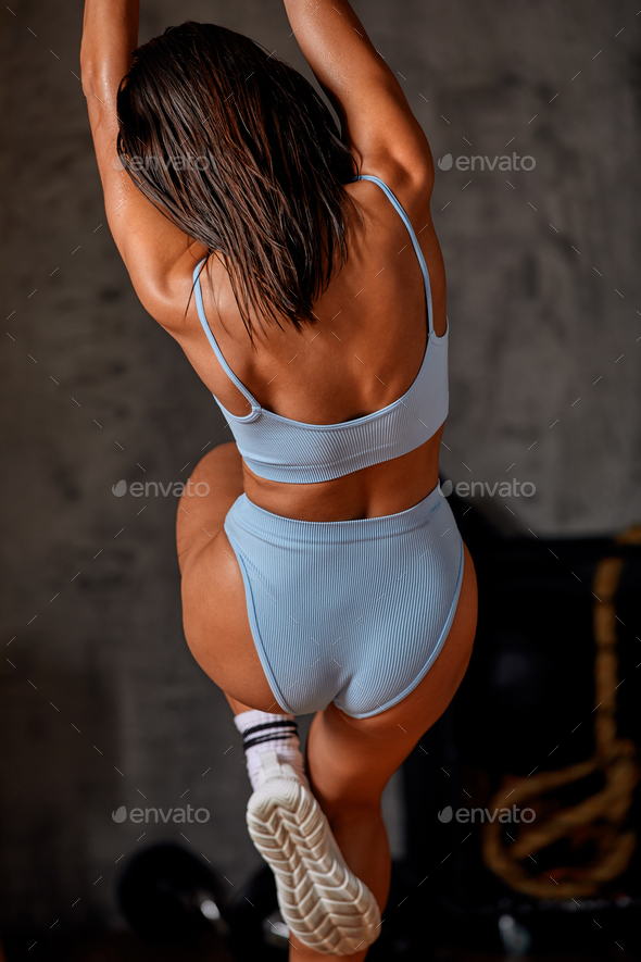 Working out Young athletic sportswoman exercising on gymnastic rings at gym  Exercising woman holding gymnast rings and looking up. Workout at gym.  Concept of power, strength, healthy lifestyle, sport. Stock Photo