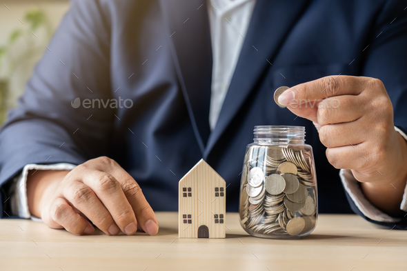 Business man savings money coins in jar for new buy or rent house