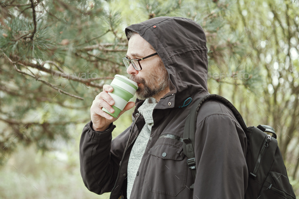 Bearded man drinks from reusable silicone mug. Camping, hiking, sustainable consumption. - Stock Photo - Images