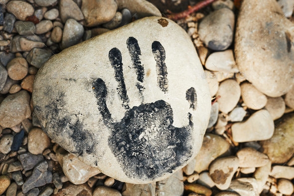 Hand print on stone. Human imprint. Close up of handmark. Sign left by human. Black print. Identity