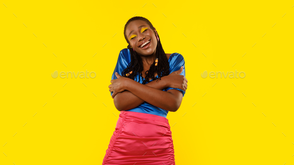 Black Woman Hugging Herself With Eyes Closed Over Yellow Background