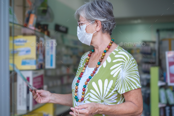 Senior woman wearing mask in drugstore pharmacy to buy medical products