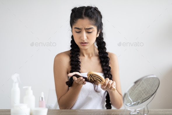 Young Indian Woman Having Problem While Brushing Her Hair At Home