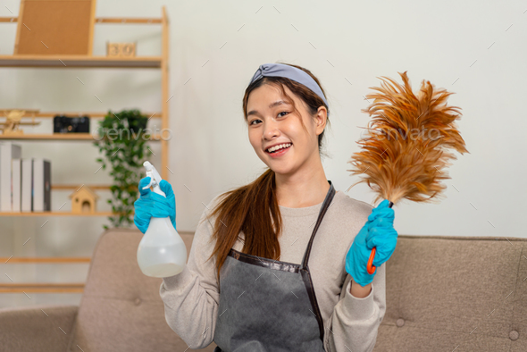 Housekeeper is wear protective gloves to holding feather duster and  cleanser bottle for cleanups
