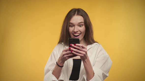 Young Adult Caucasian Woman is Celebrating an Achievement on a Bright Yellow Background alt