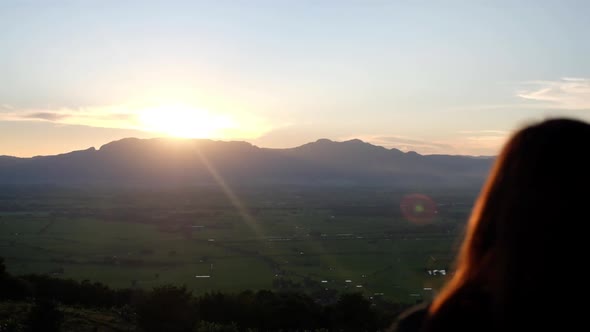 Slow motion rear view of a woman watching sunset and mountain views in the evening