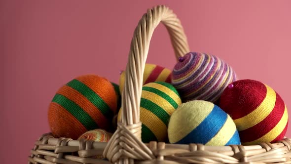 Rotation of Colorful Easter Egg in Basket Made From Threads Isolated on Pink Background