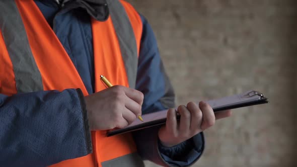 The foreman works with documentation and drawings at the construction site of a high-rise building. alt